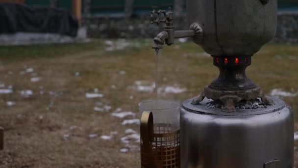 Gegoten thee in een beker in de achtertuin tijdens het koude seizoen. grote oude Samowar. Slow motion — Stockvideo