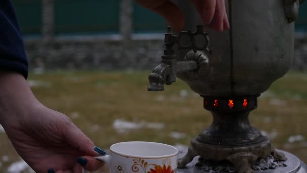Наливали чай в кружку на заднем дворе во время холодного сезона. Большой старый самовар. замедленное движение — стоковое видео