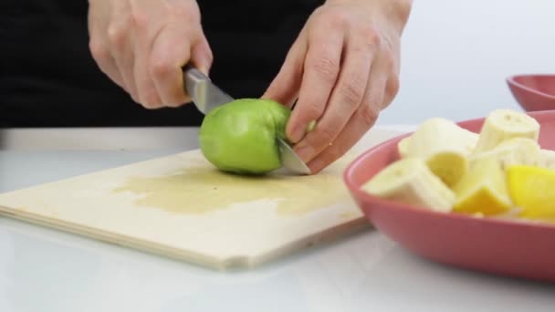 Mujer cortar el kiwi en una tabla de madera en la cocina. — Vídeos de Stock