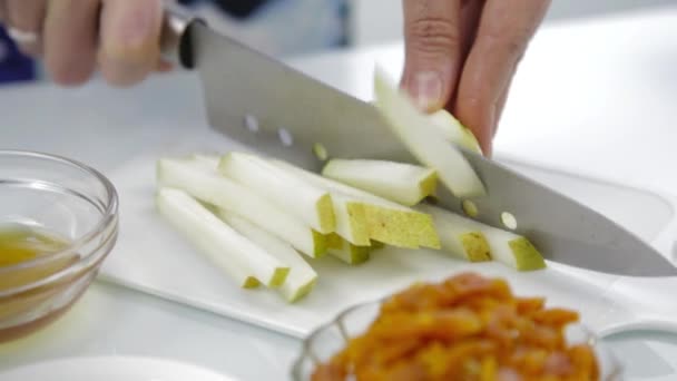 Primer plano de las mujeres manos cortando pera en la tabla de cortar en una cocina. cocinar alimentos saludables. 4K — Vídeo de stock