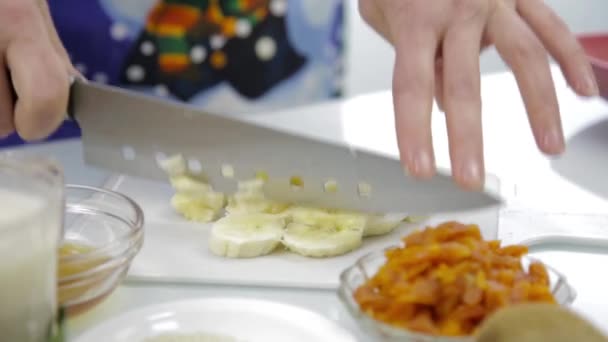 Rebanando plátano con cuchillo en la tabla de cortar. Preparación de alimentos saludables — Vídeo de stock