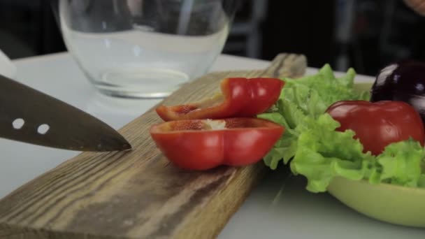 Kvinnans händer skivning söt röd paprika på en trä skärbräda. Skära grönsaker på ett köksbord — Stockvideo