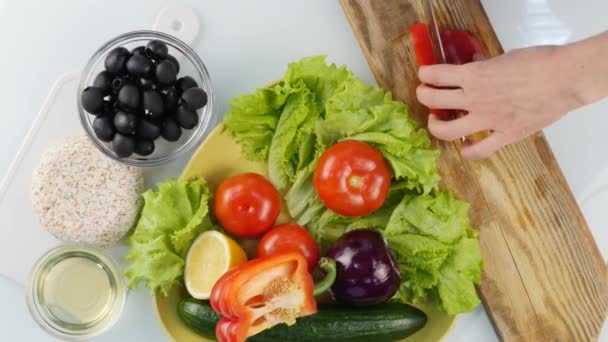 Vista superior. Mujeres manos rebanando pimiento rojo dulce en una mesa de cocina. Cortar verduras en una tabla de cortar de madera. 4K — Vídeo de stock