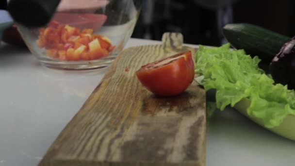 Mujer cortando tomate en una mesa de cocina. rebanar verduras en una tabla de cortar de madera — Vídeos de Stock