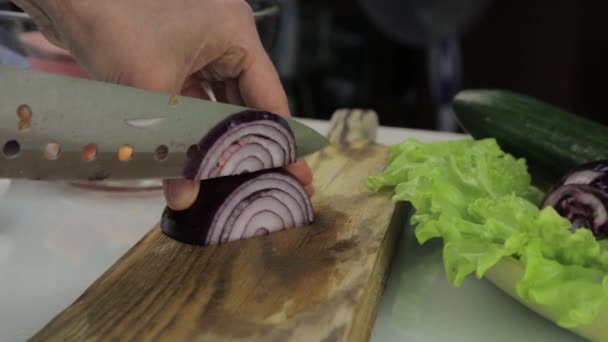 Corte de cebolla roja en tabla de madera. Las manos femeninas cortan la cebolla en la cocina. rebanar verduras — Vídeos de Stock