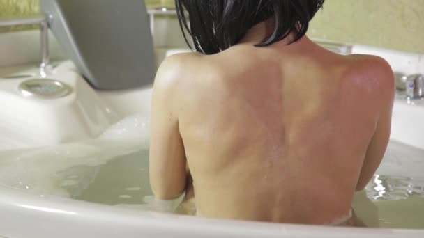 Красивая женщина принимает ванну с пеной. Вид сзади, обнаженная женщина сзади — стоковое видео
