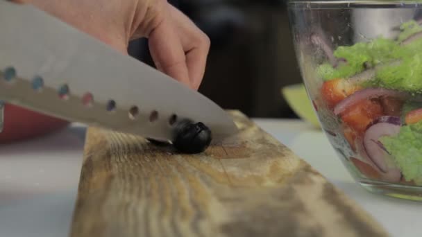 Frau schneidet Oliven für Pizza auf einem Küchentisch. Gemüse auf einem hölzernen Schneidebrett schneiden — Stockvideo