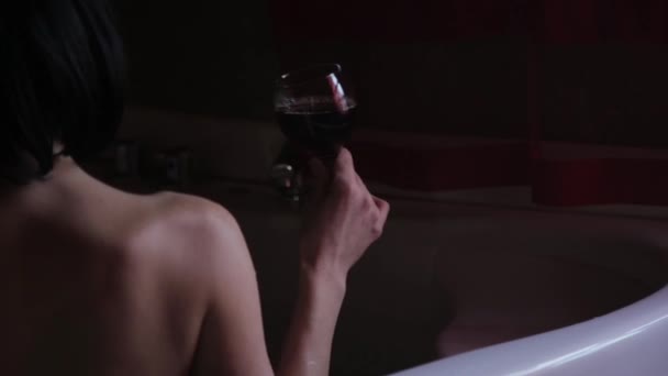 Вид на красивую молодую женщину, расслабляющуюся в ванной и пьющую красное вино — стоковое видео