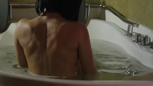 Красивая женщина принимает ванну с пеной. Вид сзади, обнаженная женщина сзади. замедленное движение — стоковое видео