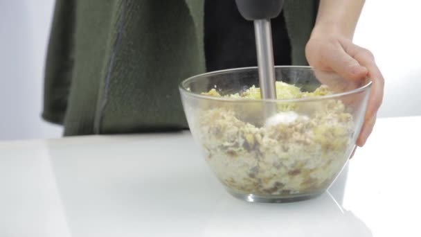 Женщина смешивает орехи с сухофруктами в стеклянной миске. приготовление здоровой пищи — стоковое видео