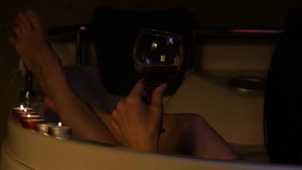 Vista posterior de la hermosa mujer joven que se relaja en un baño y beber vino tinto. cámara lenta — Vídeo de stock
