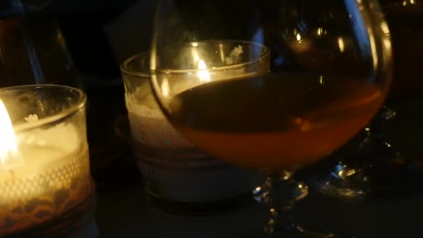 Cognac glas på ljusskenet med träfat i romantisk kväll. slowmotion — Stockvideo