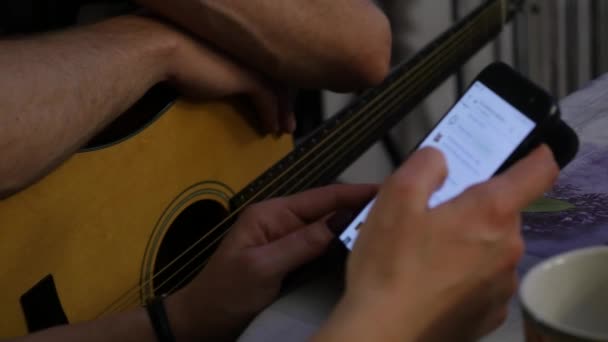 Руки крупным планом, практикующиеся в игре на гитаре и руках с телефоном. 4K — стоковое видео