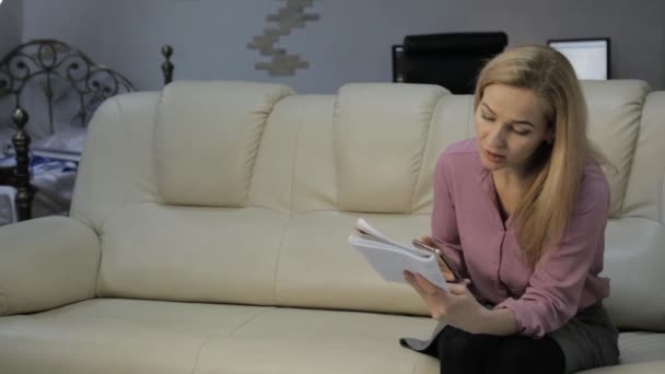 Blond Kvinna Soffa Läser Sina Anteckningar Anteckningsbok Och Kontrollerar Anteckningar — Stockvideo