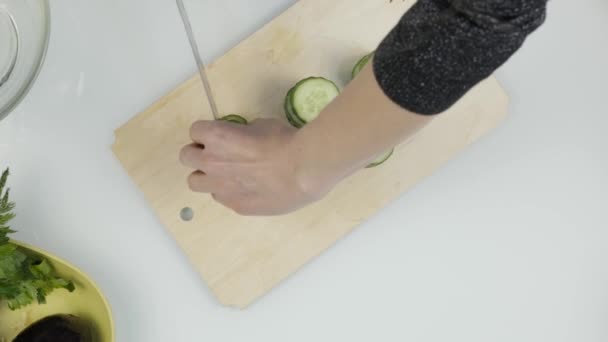 Cortar pepino para lechuga. Cortar verduras en una tabla de cocina de madera. Vista superior 4K — Vídeos de Stock