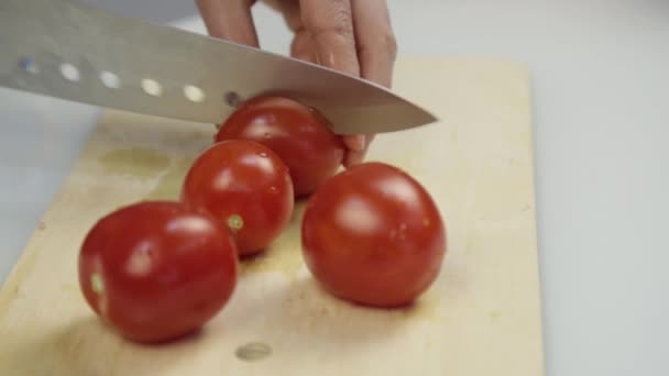 Женщины с помощью кухонного ножа режут свежие помидоры на деревянной доске. Нарезание помидоров для салата или пиццы — стоковое видео