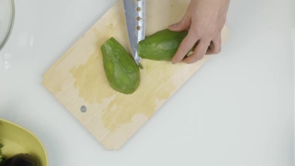 Snij een avocado in stukjes. Snijden van vruchten voor sla. Bovenaanzicht 4k — Stockvideo