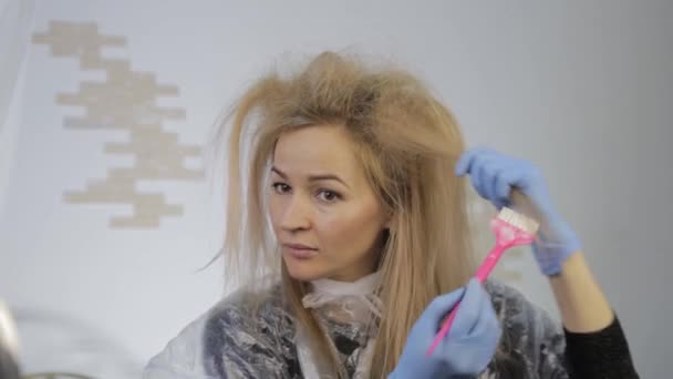 Femme blonde se teint les cheveux elle-même. Coloriage des cheveux à la maison . — Video