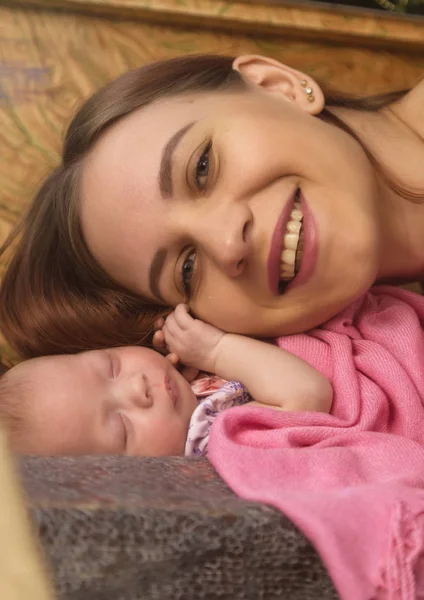 Közelkép csinos nő csókok egy újszülött a karjában — Stock Fotó