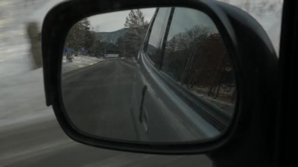 Reflexión paisaje montañoso en el espejo retrovisor lateral del coche. temporada de invierno. cámara lenta — Vídeo de stock