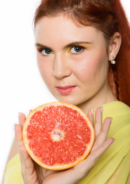 Junge rothaarige Frau mit einer Grapefruit auf weißem Hintergrund. Konzept der gesunden Ernährung — Stockfoto