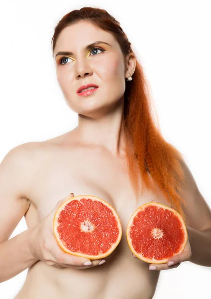 Mujer pelirroja joven con un pomelo sobre un fondo blanco. concepto de alimentación saludable — Foto de Stock