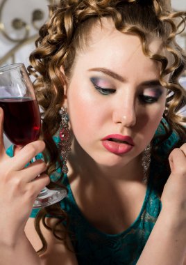 gizemli genç kıvırcık kadın yatakta istirahat ve kırmızı şarap içiyor