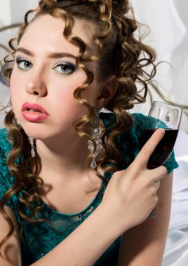 gizemli genç kıvırcık kadın yatakta istirahat ve kırmızı şarap içiyor