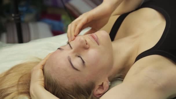 Mujer rubia haciendo auto-masaje, masaje facial tumbado en la cama en casa — Vídeo de stock