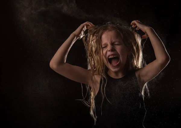 Junges Mädchen mit lebendigen Emotionen, das unter Wassertropfen tanzt. Kind schreit auf dunklem Grund mit Wasserspritzern — Stockfoto