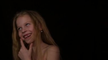 young girl with live emotions under water drops. child screaming on a dark background. expression of different emotions. slow motion