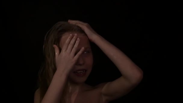 Giovane ragazza con emozioni vive sotto gocce d'acqua. bambino urla su uno sfondo scuro. espressione di emozioni diverse. rallentatore — Video Stock