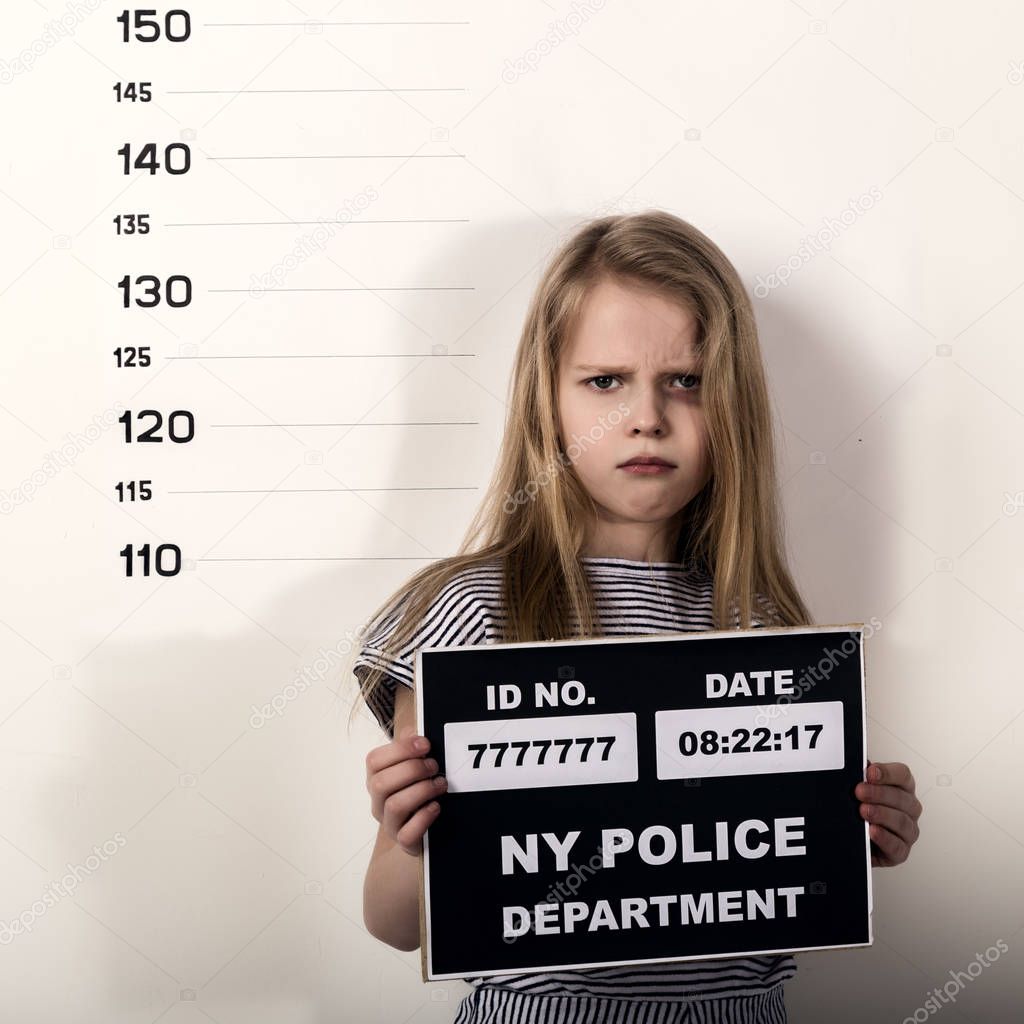Young beautiful blonde child with a sign covers his face with his hand, Criminal Mug Shots