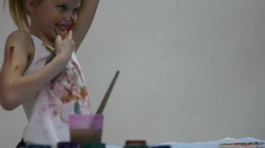 Sevimli küçük kız ressam masanın üzerine çizer ve giysilerini kendini. yavaş çekim