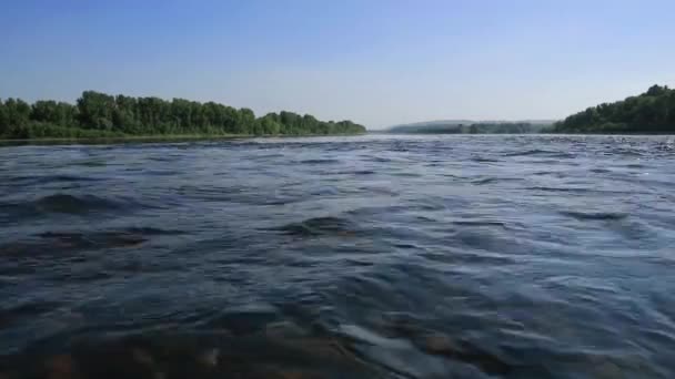Flusso veloce nell'ampio fiume poco profondo, vista su una pietra in fondo attraverso l'acqua. bagliore del sole sull'acqua — Video Stock