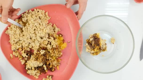 Mujer mezcla frutos secos con frutas secas en un recipiente de vidrio. cocinar alimentos saludables. vista superior 4K — Vídeos de Stock