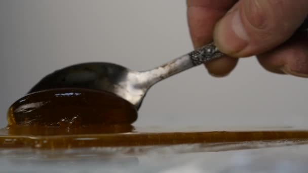 スプーンに蜂蜜を注ぐ。蜂蜜の表面に滴下します。スローモーション. — ストック動画