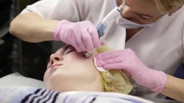 young woman with problem skin, mechanical deep face cleaning. beautician cleanses the womans skin with cosmetic equipment