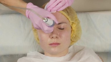 young woman with problem skin, mechanical deep face cleaning. beautician cleanses the womans skin with cosmetic equipment. 4K