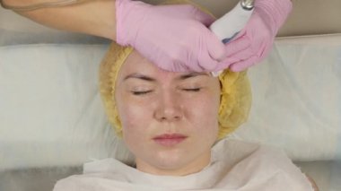 young woman with problem skin, mechanical deep face cleaning. beautician cleanses the womans skin with cosmetic equipment. 4K