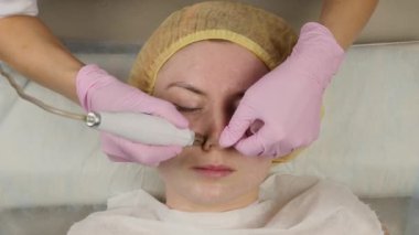 young woman with problem skin, mechanical deep face cleaning. beautician cleanses the womans skin with cosmetic equipment. 4K