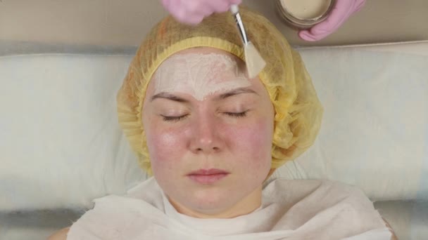 Cosmetologist que aplica a máscara facial à pele do problema. mulher jovem ter procedimentos de limpeza da pele. 4K — Vídeo de Stock