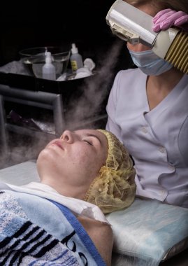 Doktor bir buhar ile kadın cilt temizler. güzellik te sorunlu genç kadın. Kozmetoloji kavramı