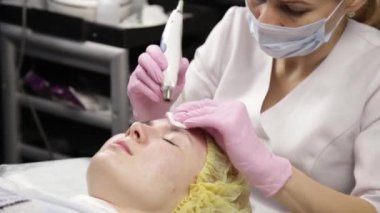 young woman with problem skin, mechanical deep face cleaning. beautician cleanses the womans skin with cosmetic equipment