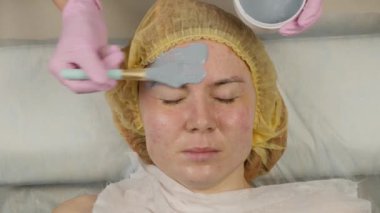 güzellik spa salonunda kadın yüzü için çamur maskesi uygulayarak. yüz gençleştirme prosedürü, spa tedavileri. 4k
