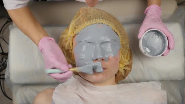 Kosmetikerin, die im Wellness-Salon eine Schlammmaske für das Frauengesicht aufträgt. Gesichtsverjüngung, Wellness-Behandlungen — Stockvideo