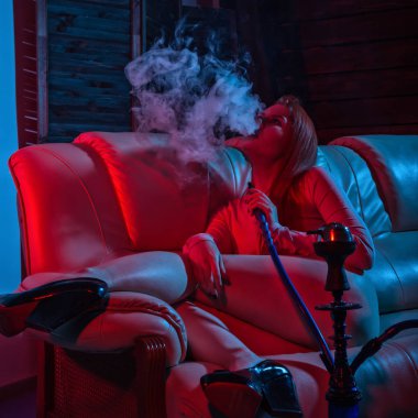 Seksi kızıl saçlı kadın kırmızı mavi tonları elektronik nargile vaping. kız darbeler beyaz doom