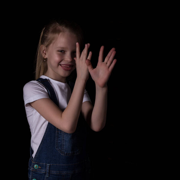 beautiful blonde little girl on a dark background. She stands in different poses and shows different emotions. free space for your text