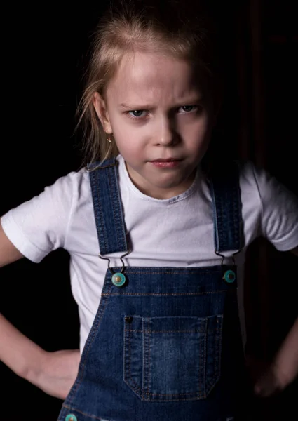 Όμορφο ξανθό κοριτσάκι σε σκοτεινό φόντο. Στέκεται σε διαφορετικές στάσεις και δείχνει διαφορετικά συναισθήματα — Φωτογραφία Αρχείου