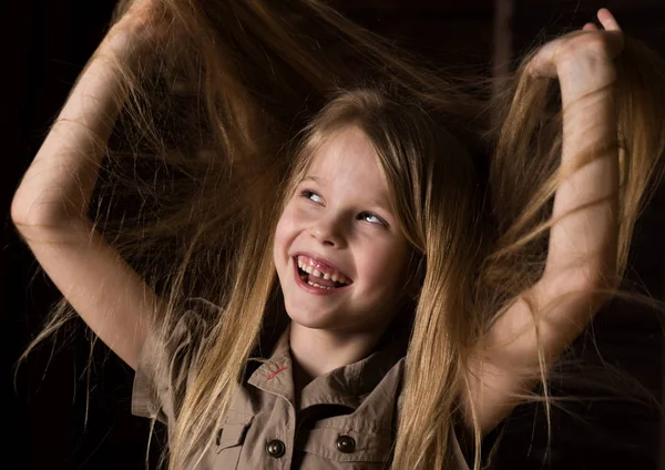 Αστείο όμορφο μικρό ξανθό παιδί με διαφορετικά συναισθήματα σε ένα σκοτεινό φόντο. όμορφη μαθήτρια που κρατάει τα μαλλιά της — Φωτογραφία Αρχείου